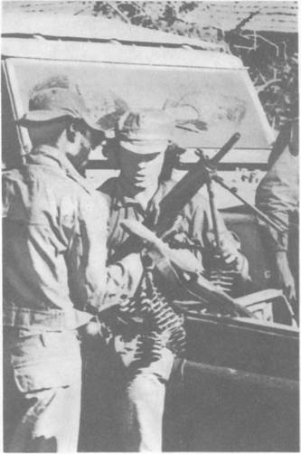 Белый наемник обучает солдата марионеточных войск обращению с оружием.